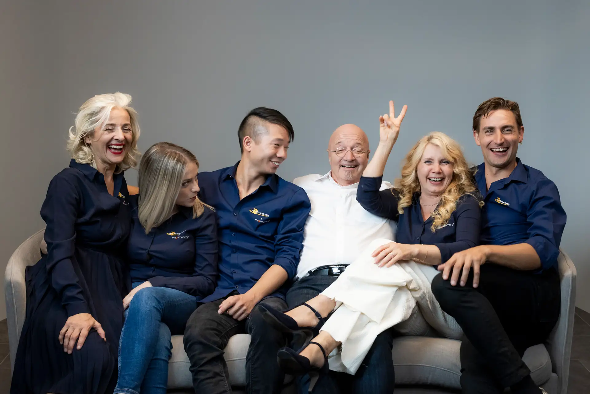 Das megaSPRACHEN-Team: Gedächtnistrainer Gregor Staub, Ljubica Negovec und die Sprachtrainer gemeinsam auf dem Sofa im Studio
